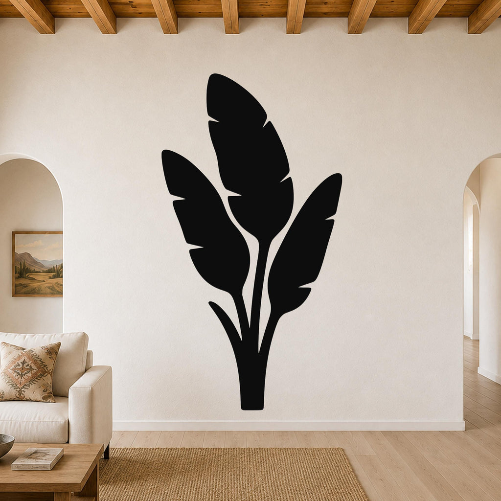 Black metal wall art featuring a tropical leaf silhouette, mounted on a living room wall above a sofa.