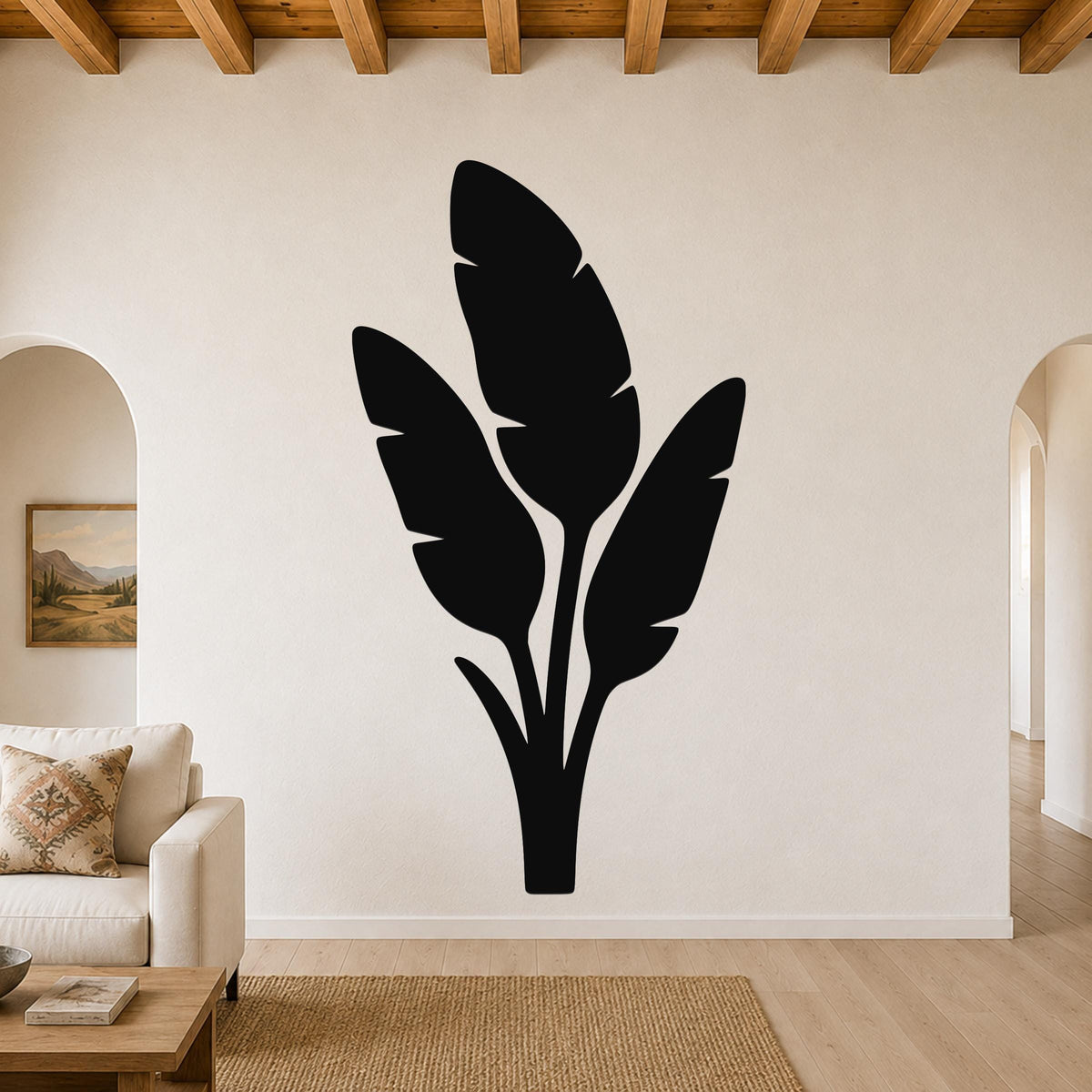 Black metal wall art featuring a tropical leaf silhouette, mounted on a living room wall above a sofa.
