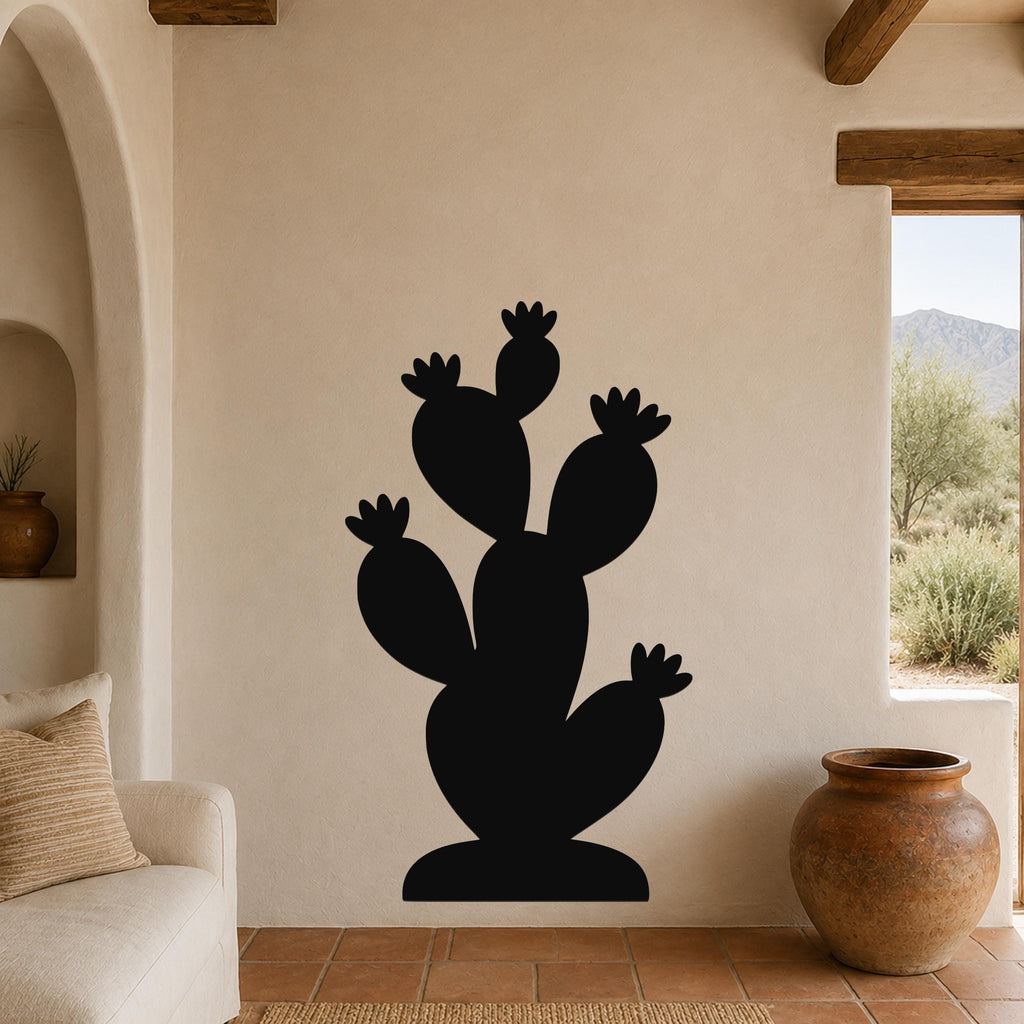 Black metal prickly pear cactus wall art with multiple pads and flower cutouts, mounted on a beige living room wall above a sofa.