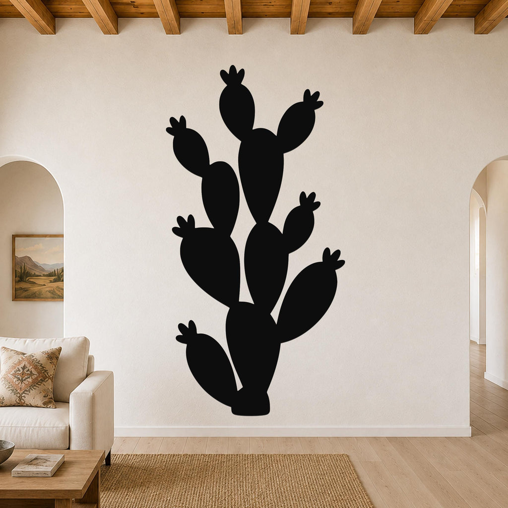 Black metal prickly pear cactus wall art with multiple segmented pads and small flower cutouts, mounted on a living room wall above a sofa.