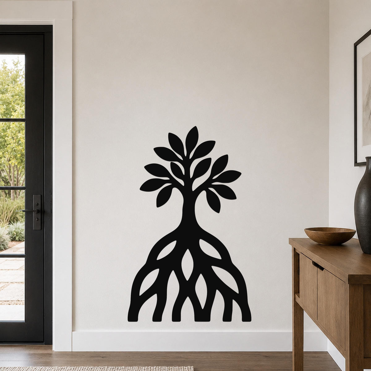 Black metal wall art silhouette of a mangrove tree with visible root system, mounted on a living room wall above a wooden console table.