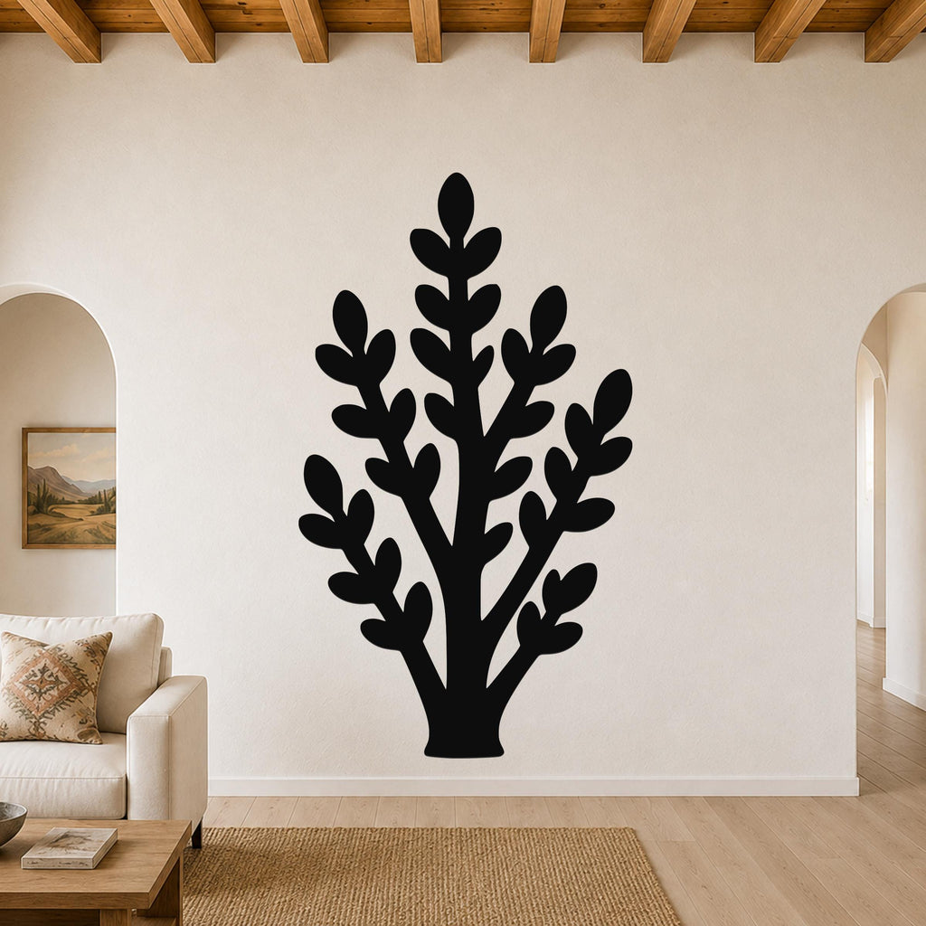 Black metal wall art in a silhouette of a jade plant with layered leaf cutouts, mounted on a living room wall above a sofa.