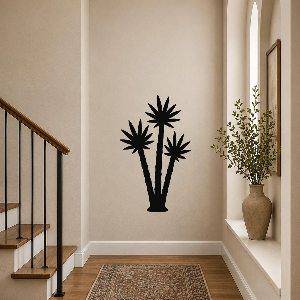 Black metal wall art featuring a silhouette of three palm trees, mounted on a hallway wall above a patterned rug near a staircase.