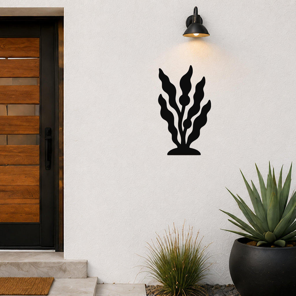 Black metal kelp wall art with flowing leaf cutouts, mounted on a white exterior wall above a potted succulent and near a front door.