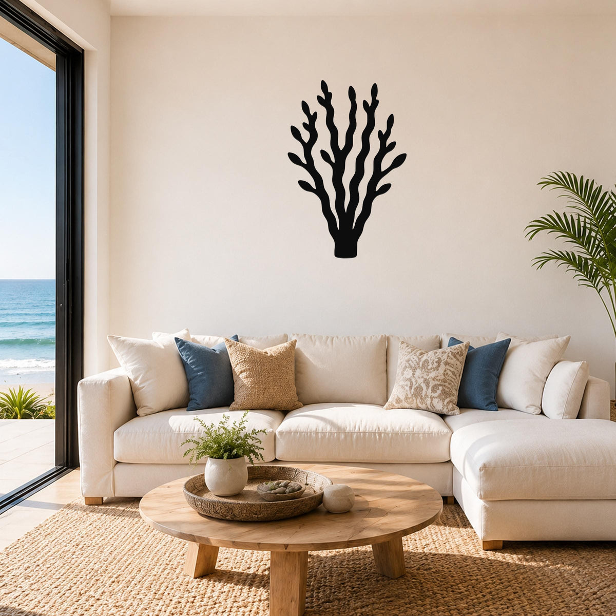 Black metal kelp wall art with branching cutouts, mounted above a white sofa in a coastal living room.