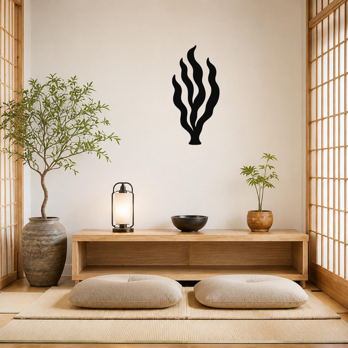 Black metal kelp seaweed wall art with flowing frond cutouts, mounted on a light wall above a wooden console in a minimalist room.