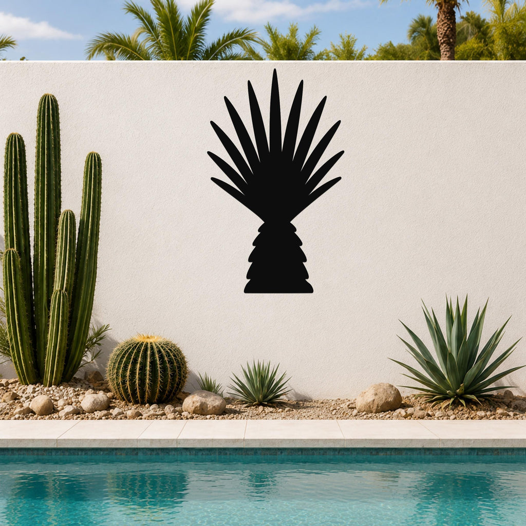 Black metal wall art cutout of a fan palm tree silhouette, mounted on a white outdoor wall above a poolside garden with cacti and succulents.