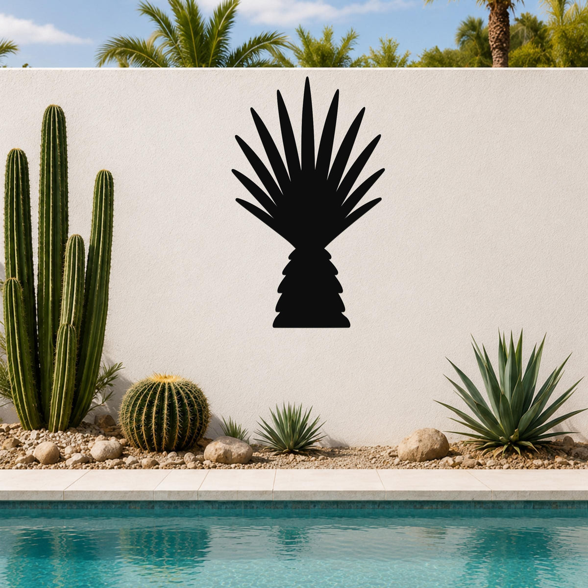 Black metal wall art cutout of a fan palm tree silhouette, mounted on a white outdoor wall above a poolside garden with cacti and succulents.