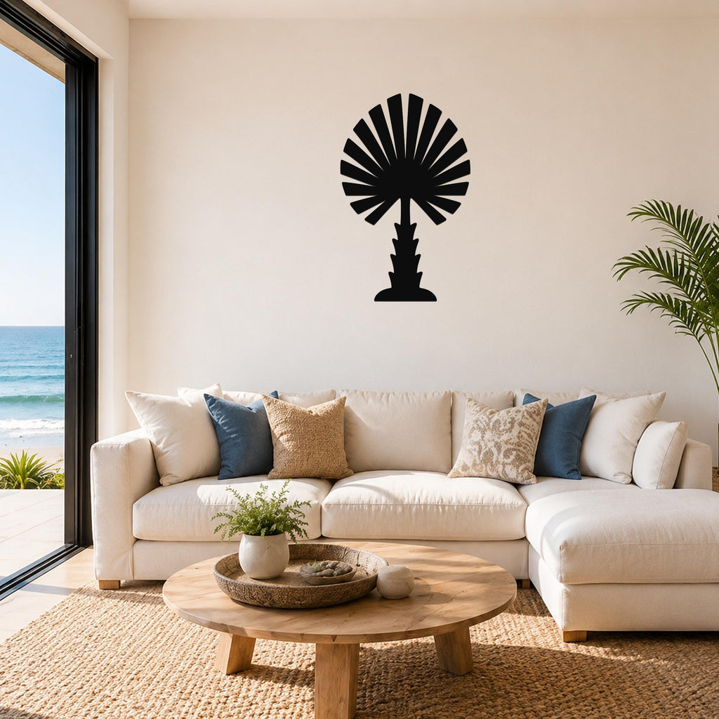 Black metal palm tree wall art with fan-shaped fronds, mounted above a white sofa in a living room with ocean views.