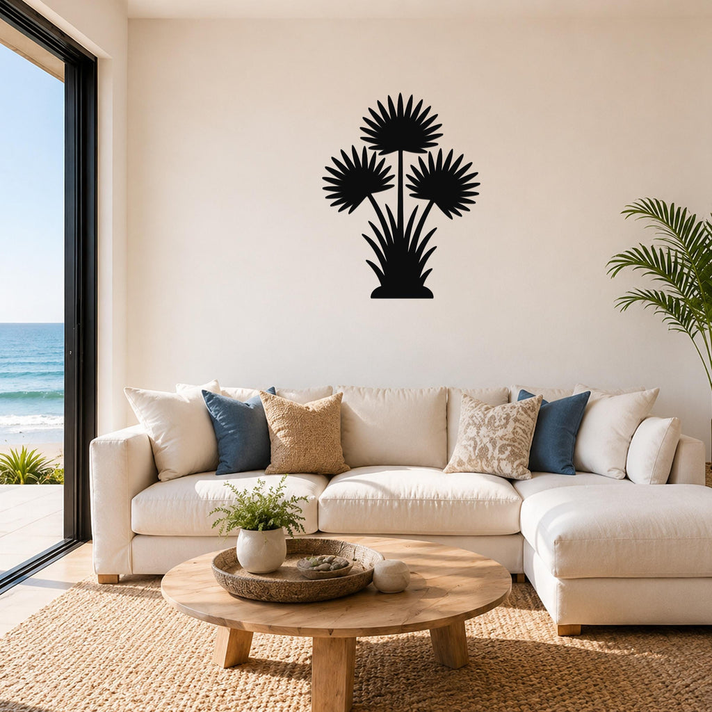 Black metal fan palm tree wall art with three frond silhouettes, mounted above a white sofa in a living room with ocean views.
