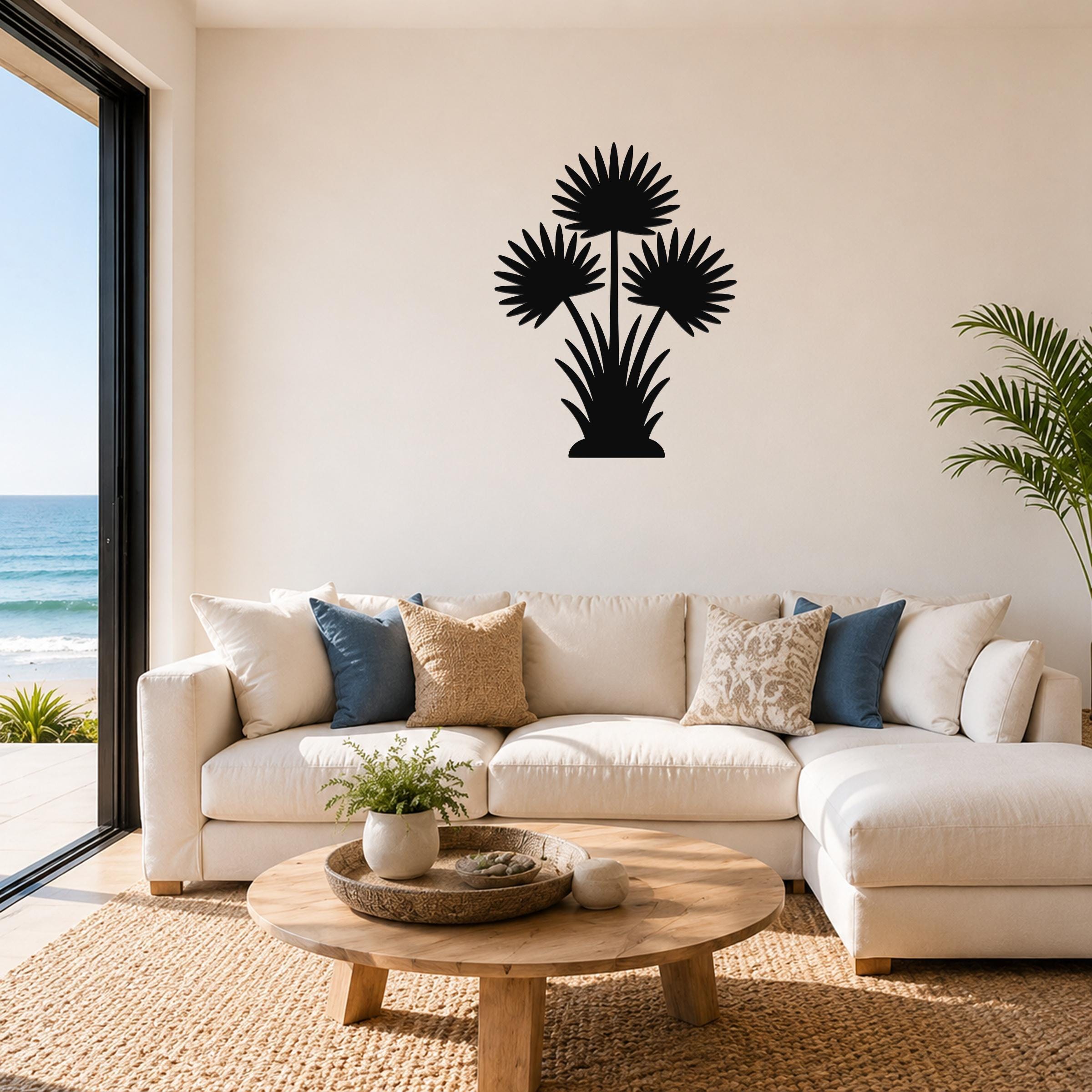 Black metal fan palm tree wall art with three frond silhouettes, mounted above a white sofa in a living room with ocean views.
