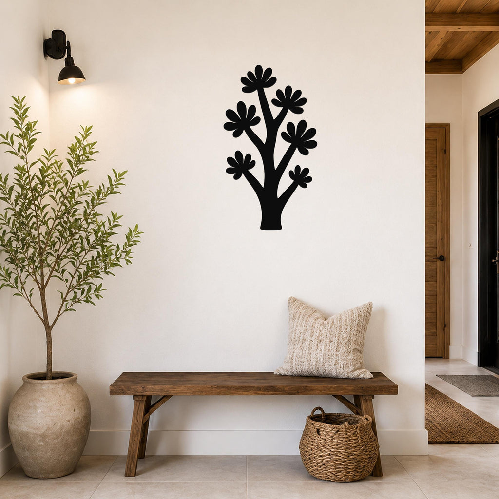 Black metal wall art in a tree silhouette with flower cutouts, mounted on a white wall above a wooden bench in a hallway.