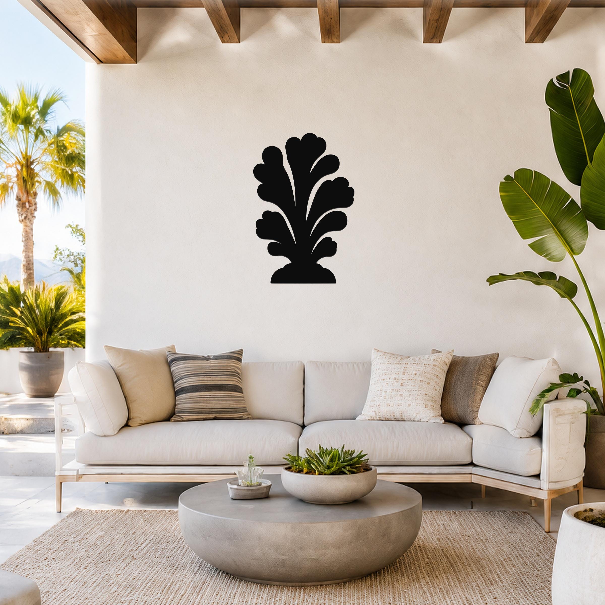 Black metal wall art in a coral silhouette design, mounted on a white wall above a light-colored sofa in a bright living room.