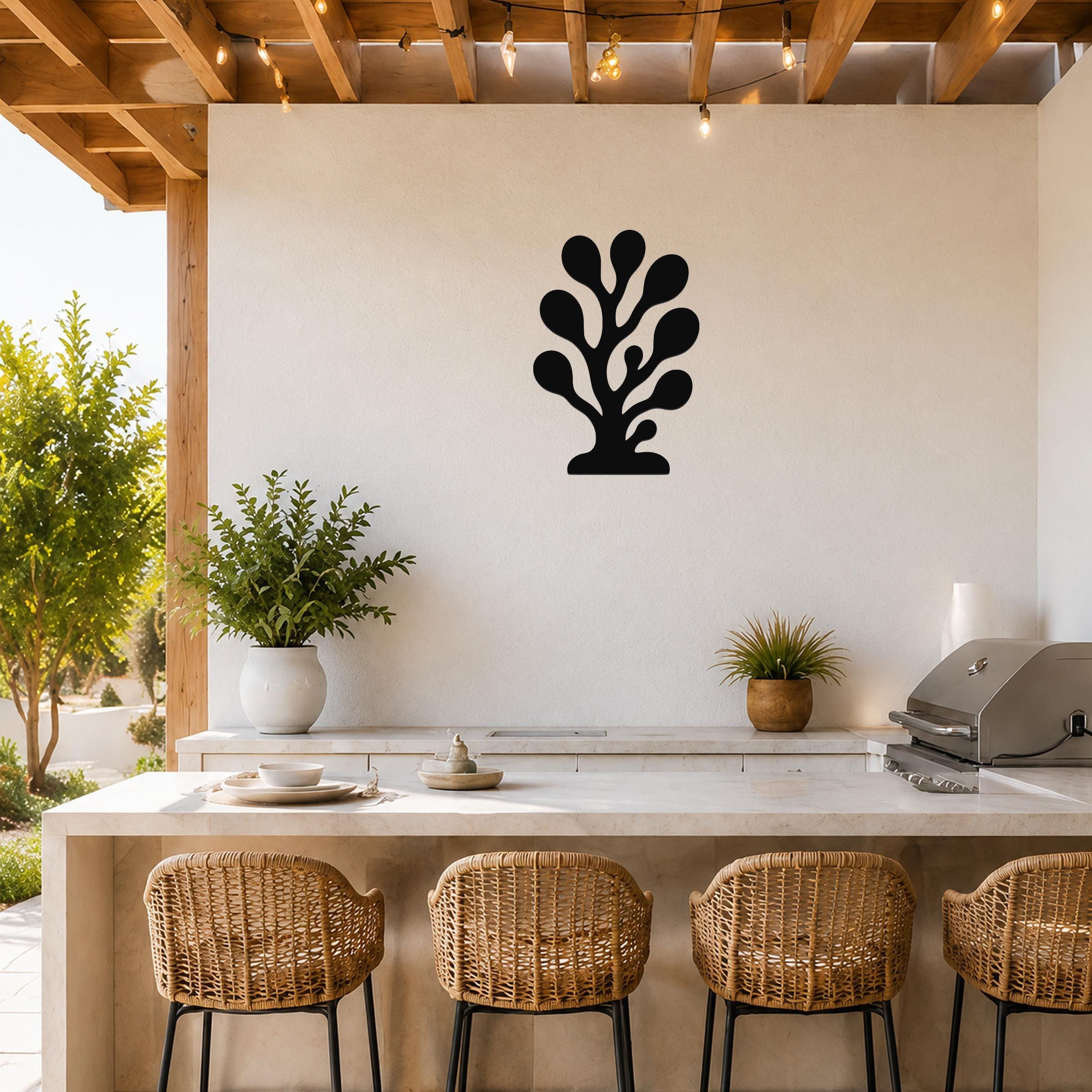 Black metal coral wall art with branching cutouts, mounted on a white outdoor wall above a kitchen counter.