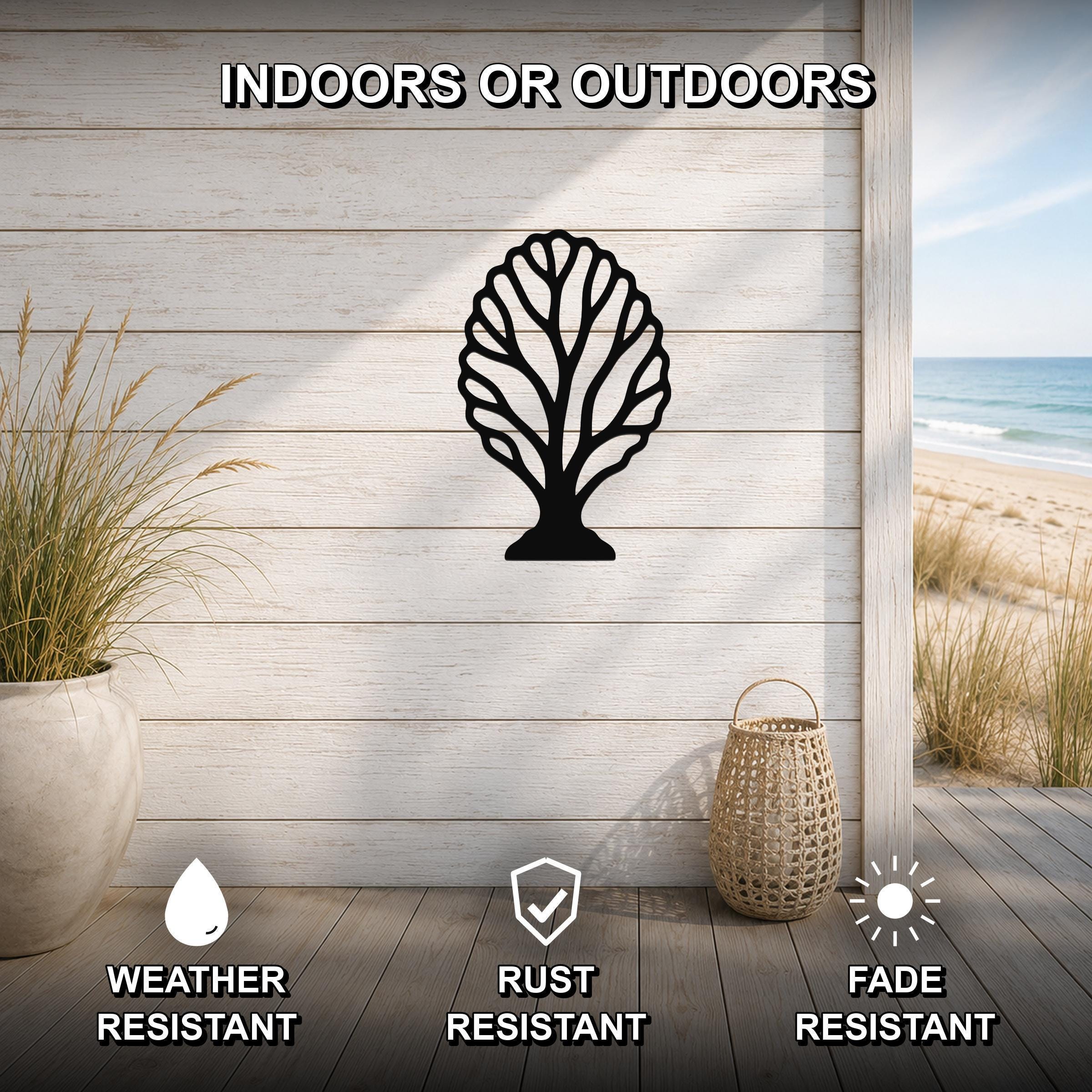 Black metal fan coral wall art with intricate branch cutouts, mounted on a light wood wall above a patio with a beach view.