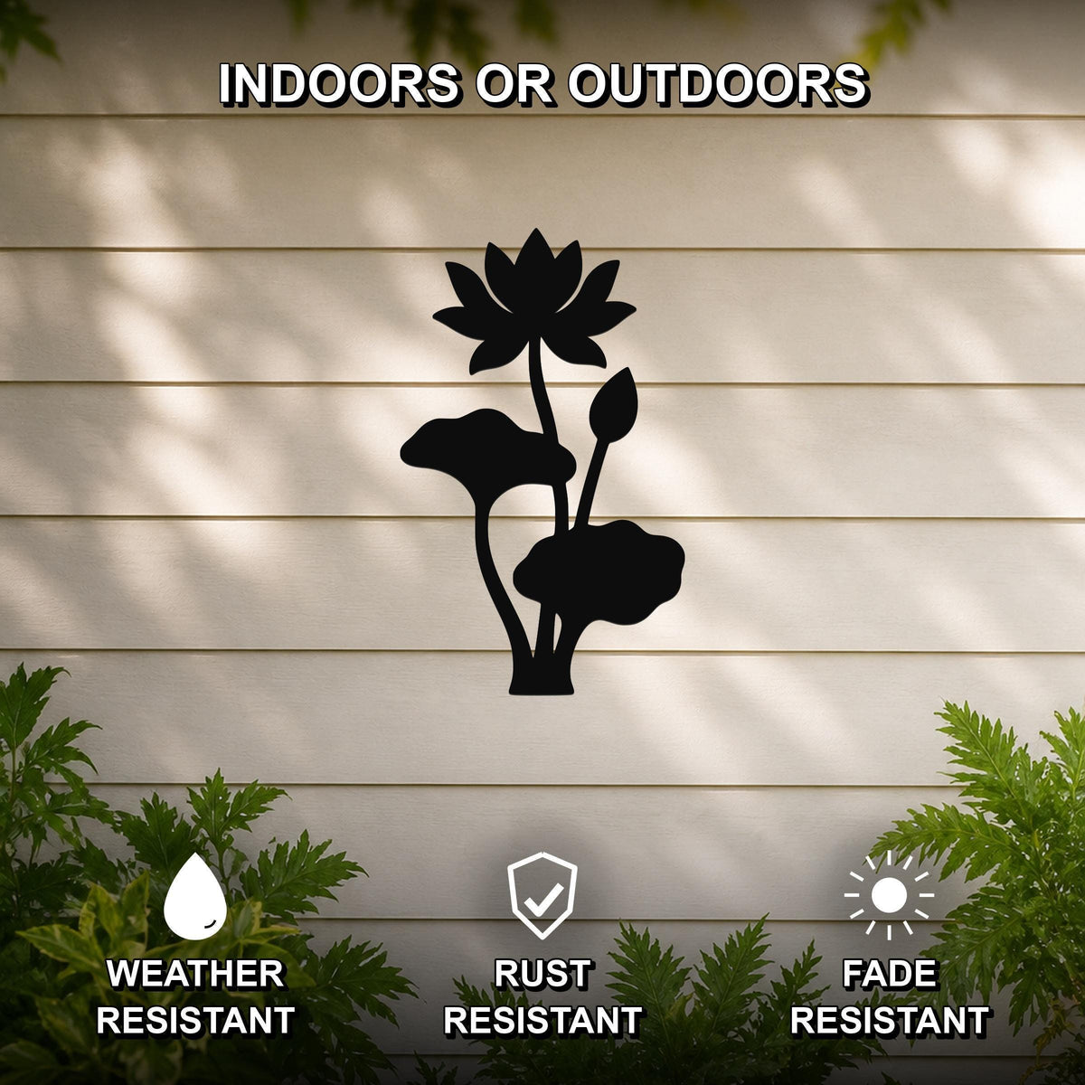 Black metal lotus water lily wall art with flower and leaf cutouts, mounted on a beige outdoor wall with greenery below.