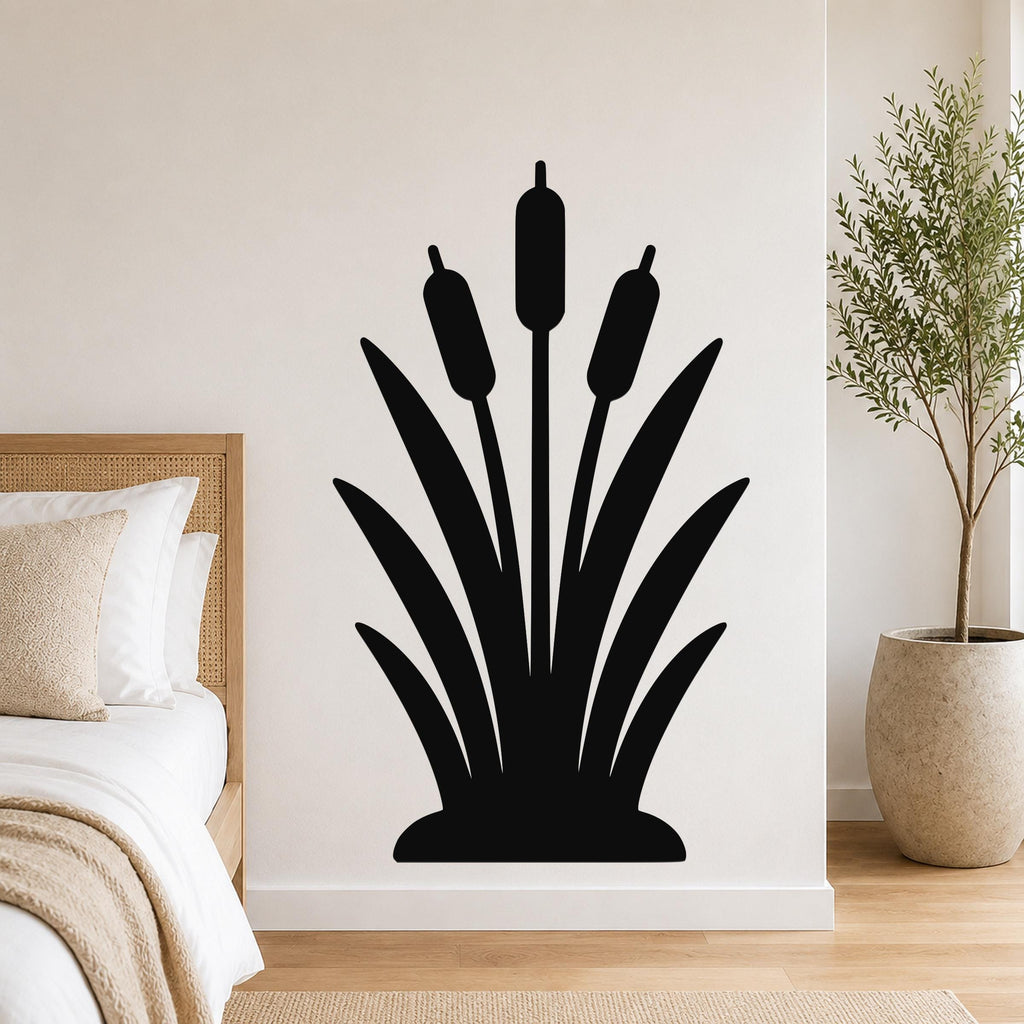 Black metal cattail wall art silhouette with three seed heads and long leaves, mounted on a bedroom wall above a bed.