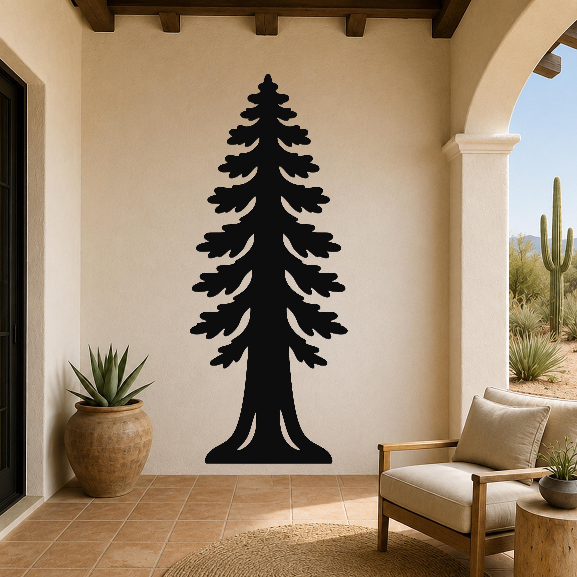 Black metal sequoia tree wall art with layered branch cutouts, mounted on a beige stucco wall in a covered patio with arched entryway and desert view.