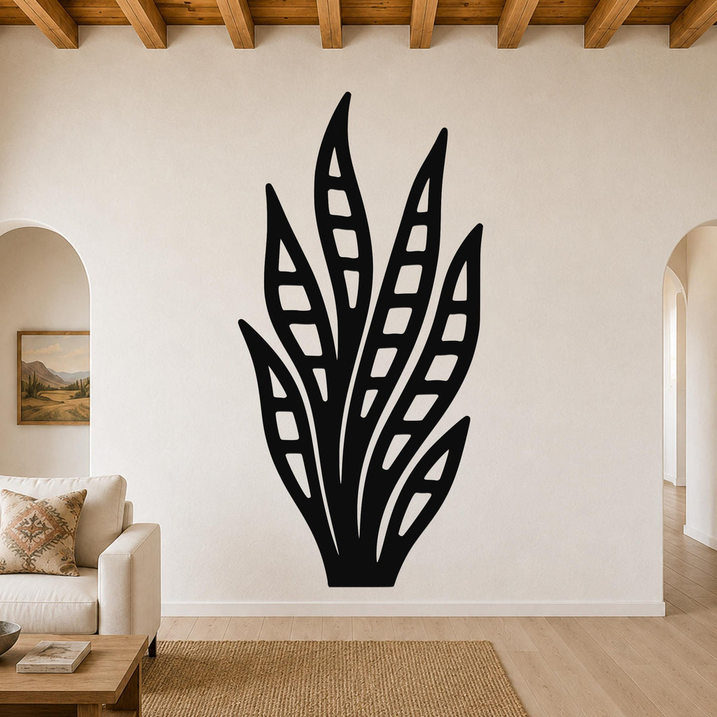 Black metal wall art in a snake plant silhouette with internal leaf cutouts, mounted on a living room wall above a sofa.