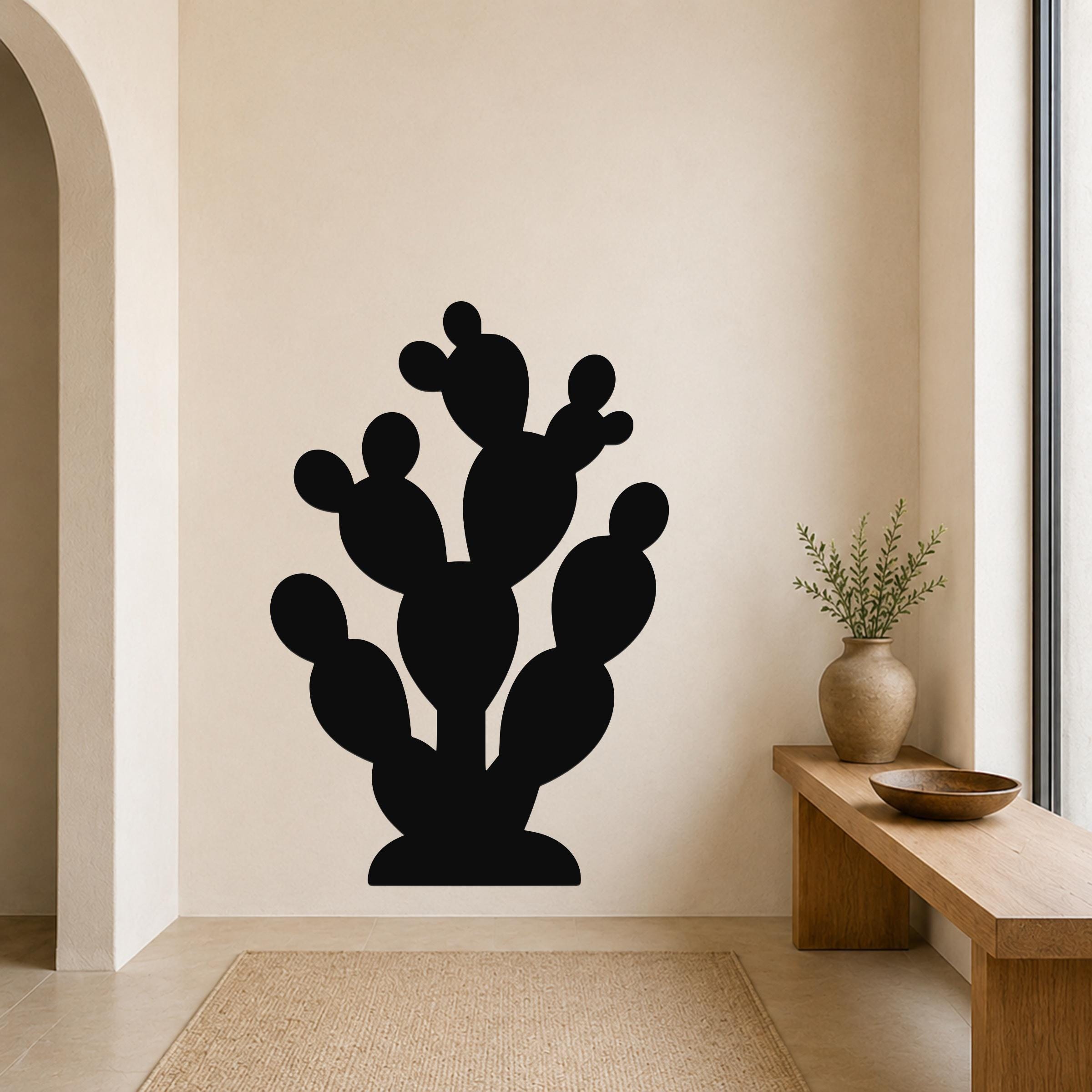 Black metal prickly pear cactus wall art with multiple rounded pads and cutout details, mounted on a beige wall above a wooden bench in a modern entryway.