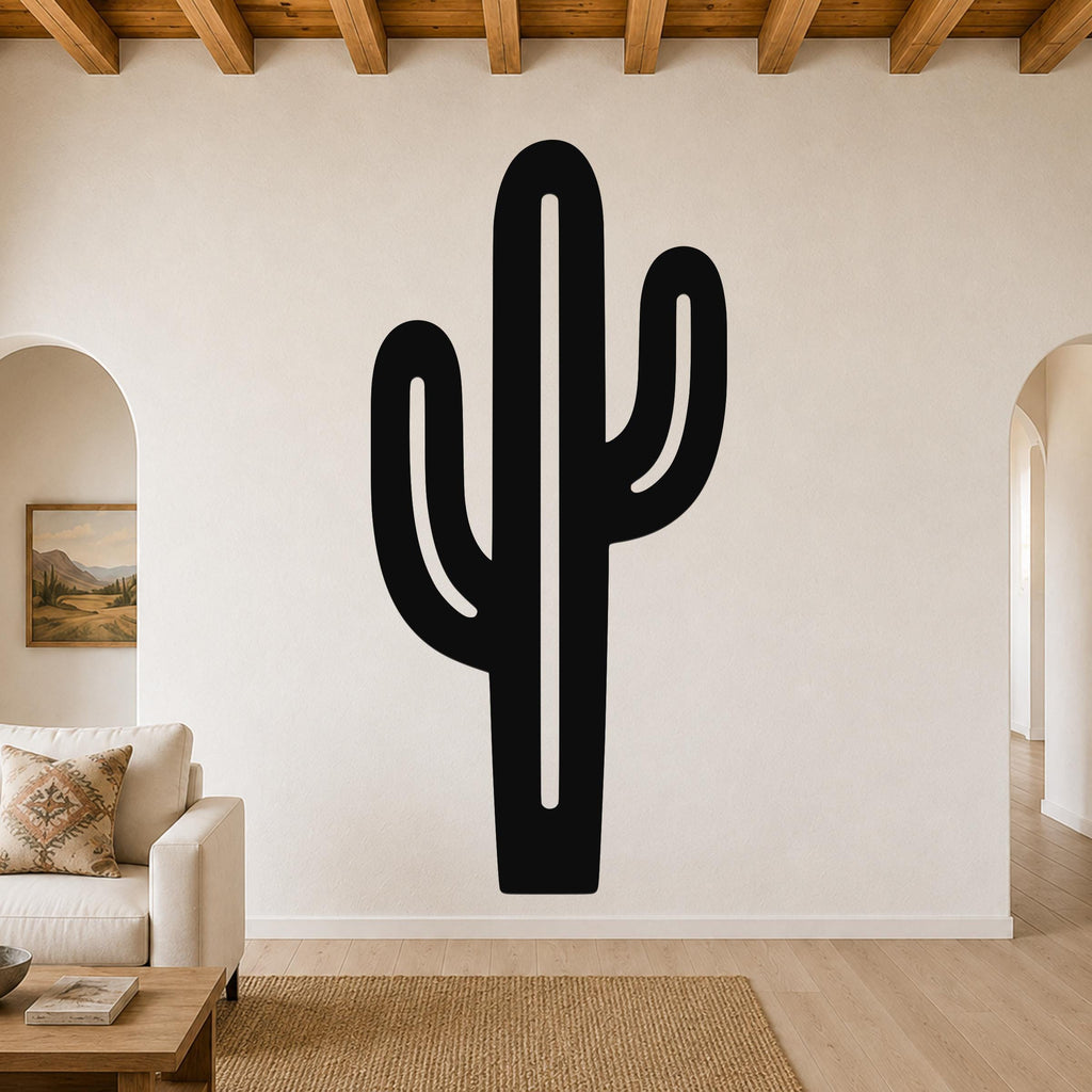 Black metal saguaro cactus wall art with cutout arms, mounted on a living room wall above a sofa.