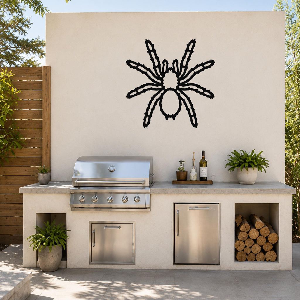 Black metal spider wall art with detailed leg cutouts, mounted on an outdoor patio wall above a stainless steel grill and counter.