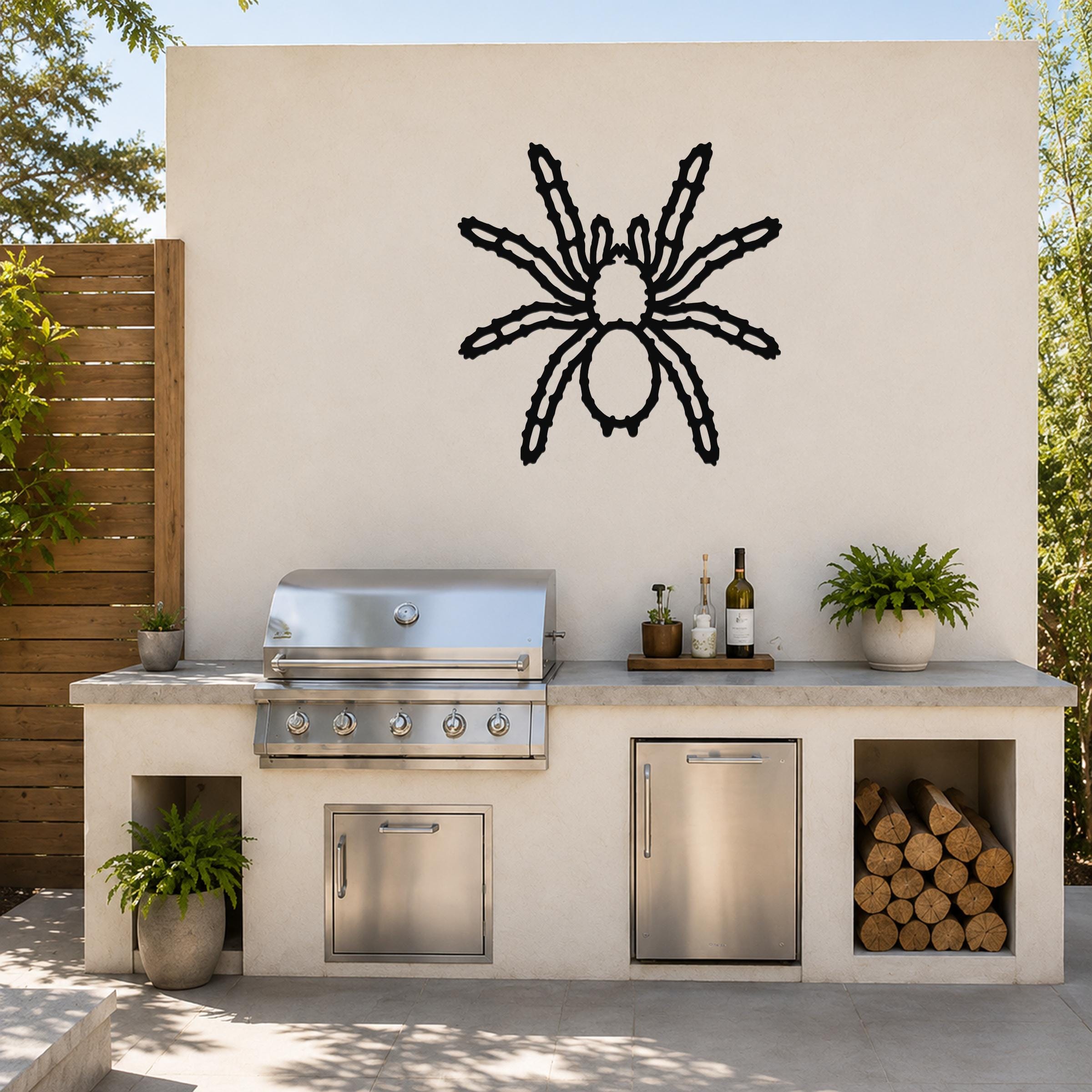 Black metal spider wall art with detailed leg cutouts, mounted on an outdoor patio wall above a stainless steel grill and counter.