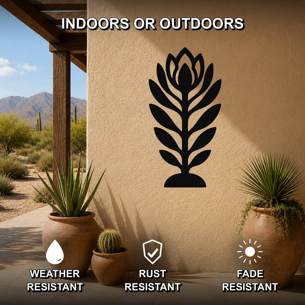 Black metal wall art in a leafy plant silhouette, mounted on an outdoor patio wall with potted succulents nearby.