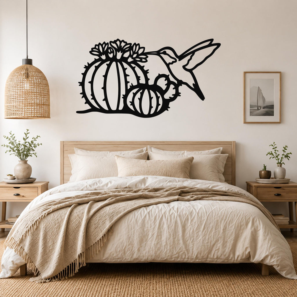 Black metal wall art featuring a hummingbird and barrel cactus with flower cutouts, mounted above a bed in a neutral bedroom.