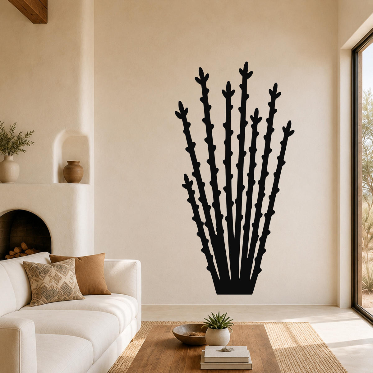 Black metal ocotillo wall art with spiky branch cutouts, mounted on a living room wall above a white sofa.