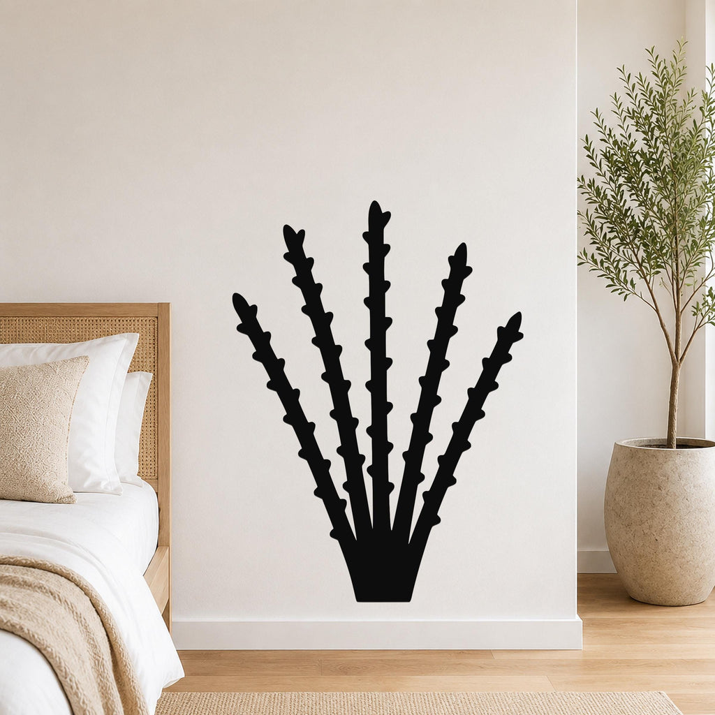 Black metal ocotillo wall art with spiky branch cutouts, mounted on a white bedroom wall above a bed.