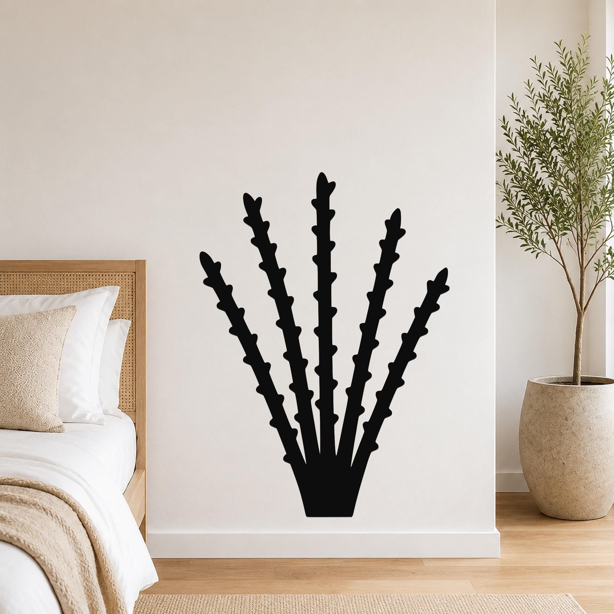 Black metal ocotillo wall art with spiky branch cutouts, mounted on a white bedroom wall above a bed.