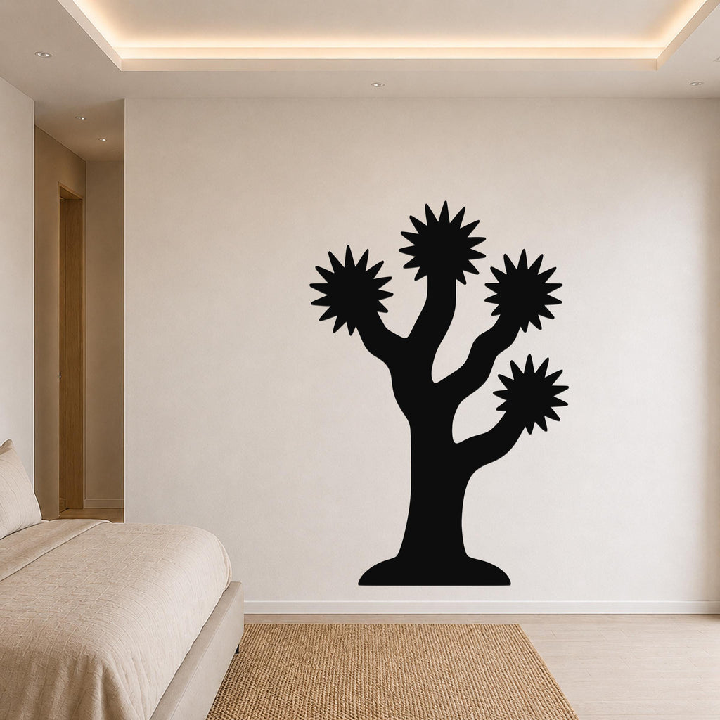 Black metal Joshua tree wall art with starburst-shaped branches, mounted on a bedroom wall above a bed.