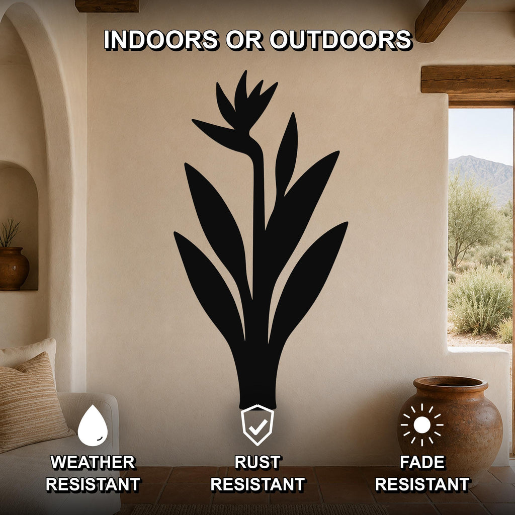 Black metal Bird of Paradise wall art silhouette mounted on a beige stucco wall in a living room, with text indicating it is weather, rust, and fade resistant for indoor or outdoor use.