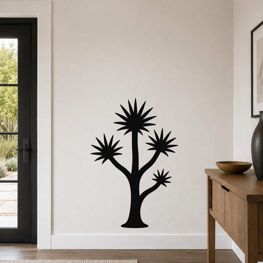 Black metal yucca wall art with starburst leaf cutouts, mounted on a light-colored wall in a modern entryway.