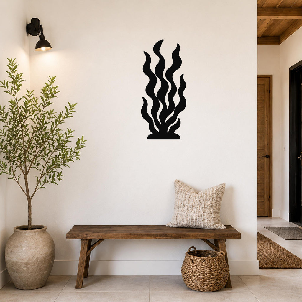 Black metal kelp wall art with wavy cutout design, mounted on a white wall above a wooden bench in a hallway.