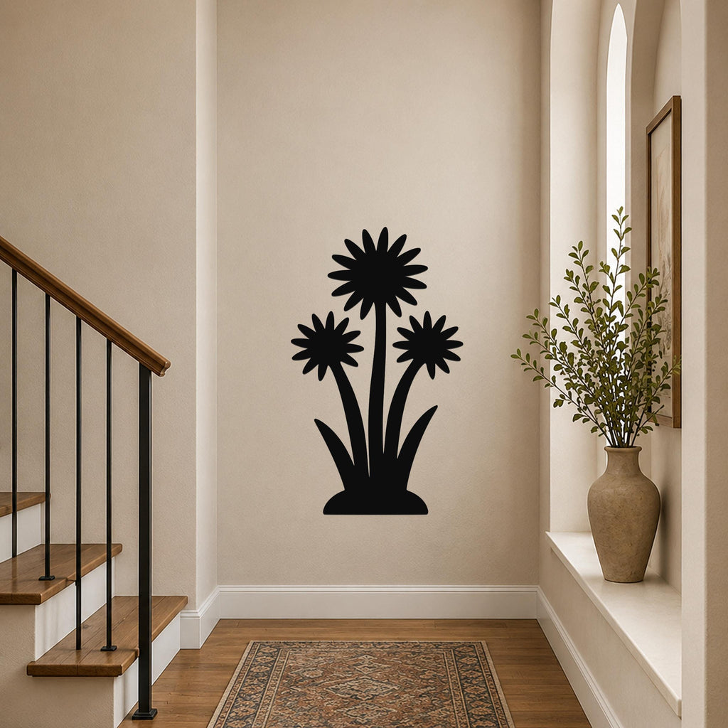 Black metal wall art featuring a silhouette of three wildflowers with layered petals and long stems, mounted on a hallway wall above a patterned rug near a staircase.