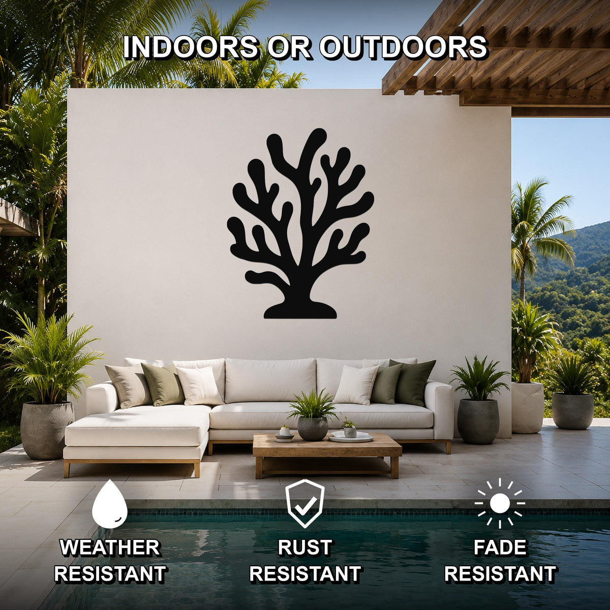 Black metal coral wall art with branching cutouts, mounted on a white outdoor wall above a sofa in a patio living area.