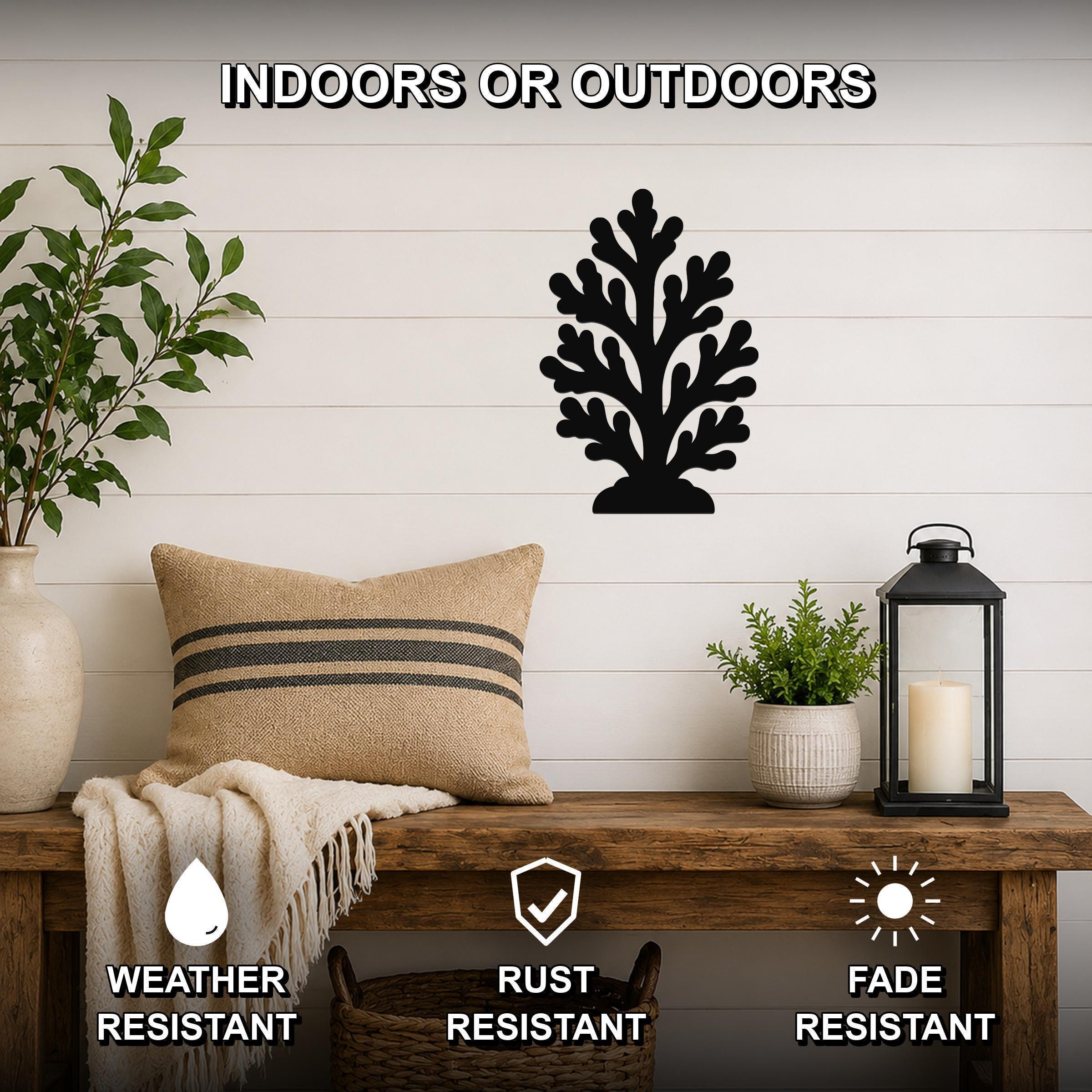 Black metal coral wall art with intricate branch cutouts, mounted on a white shiplap wall above a wooden bench in a living room.