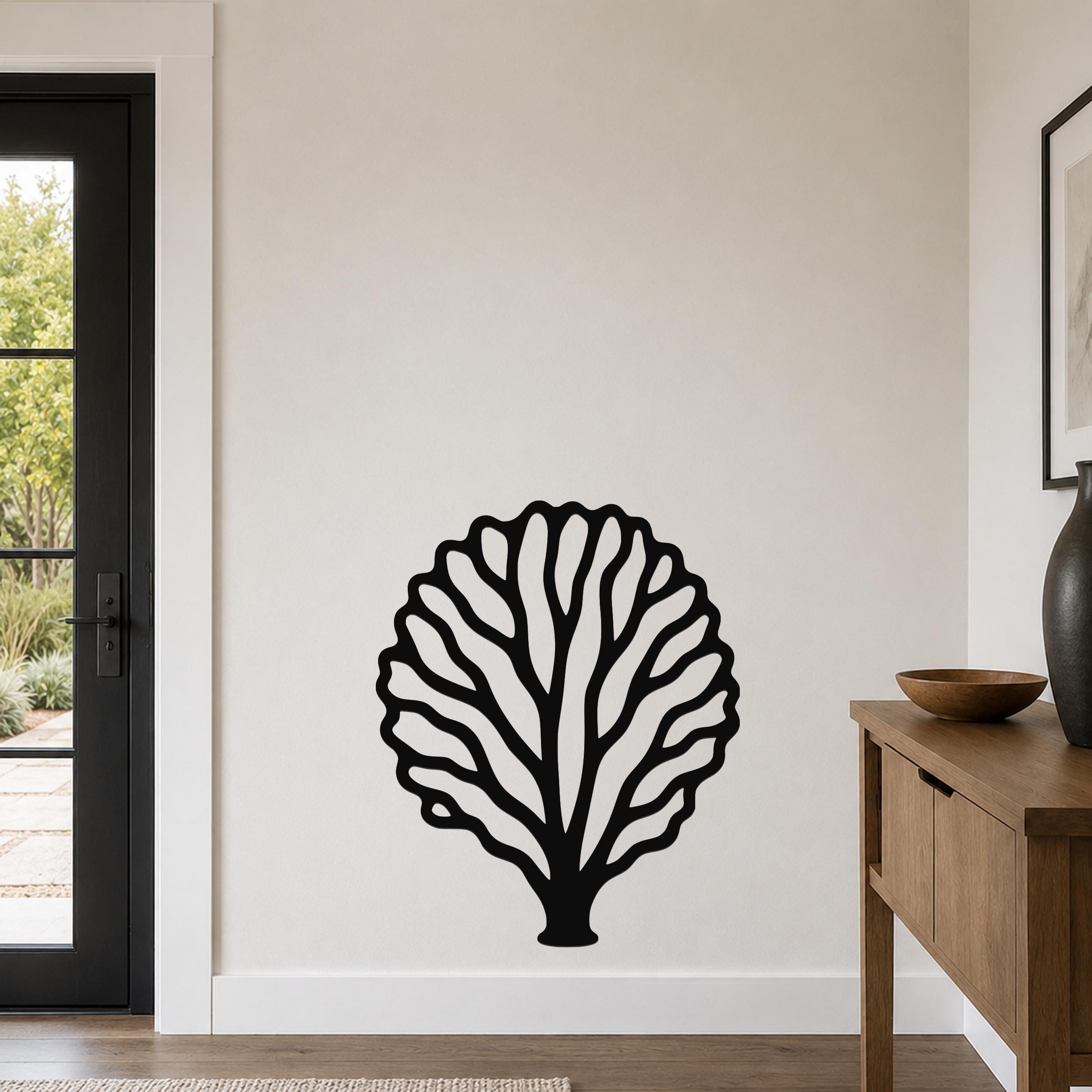 Black metal fan coral wall art with intricate branch cutouts, mounted on a living room wall above a wooden console table.