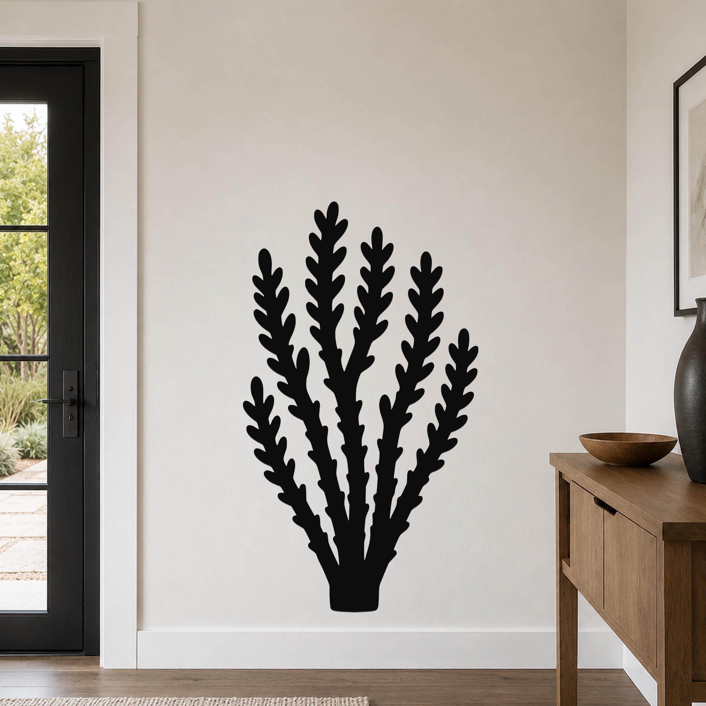 Black metal wall art in a silhouette of a branching desert plant, mounted on a light-colored wall in a living room.