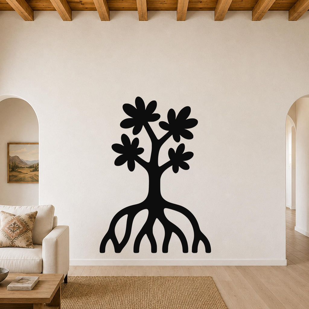 Black metal wall art in a tree silhouette with flower cutouts and exposed roots, mounted on a living room wall above a sofa.
