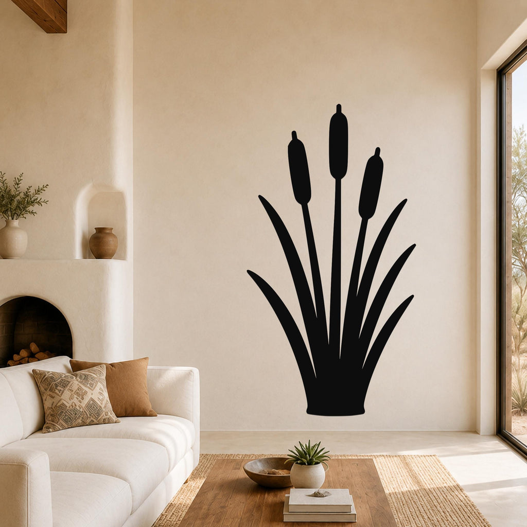 Black metal cattail wall art silhouette with three seed heads and long leaves, mounted on a living room wall above a white sofa.