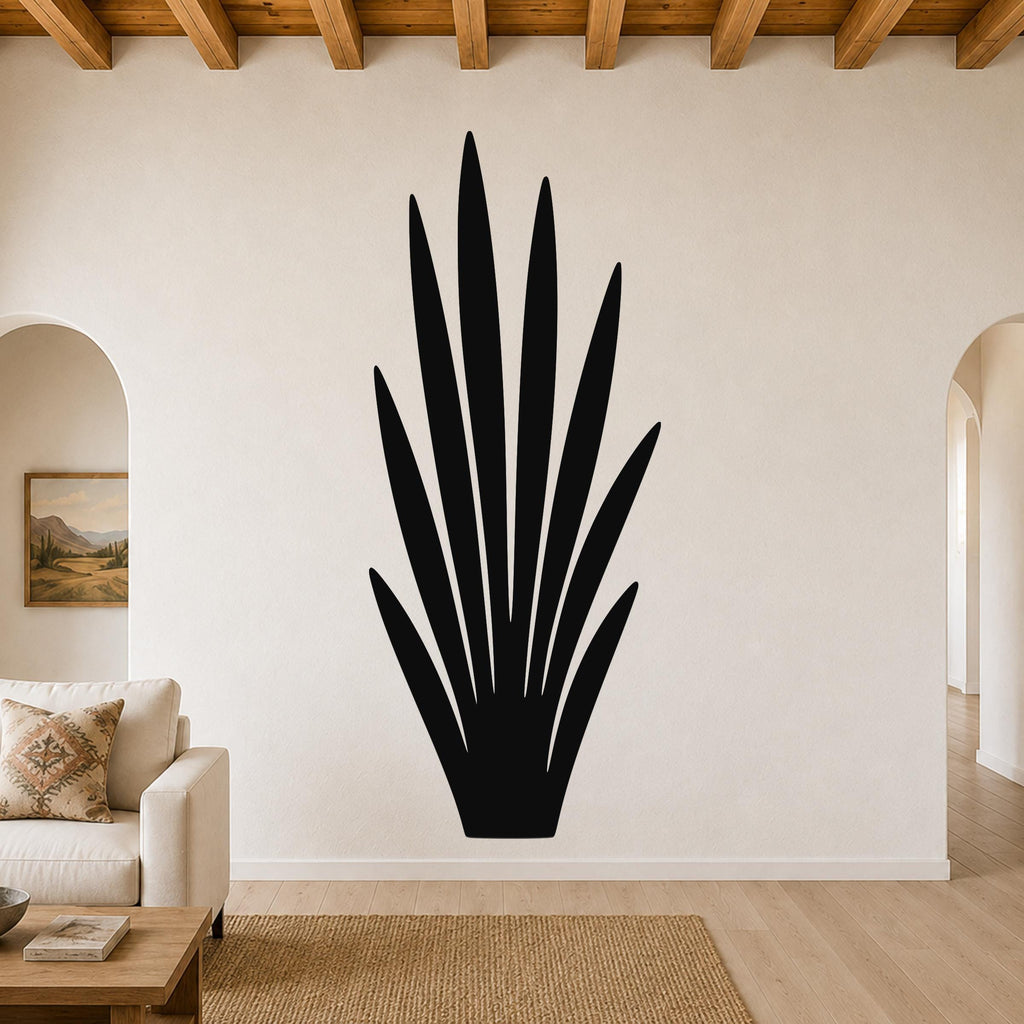 Black metal wall art in a tall, spiky agave silhouette, mounted on a living room wall above a beige sofa.