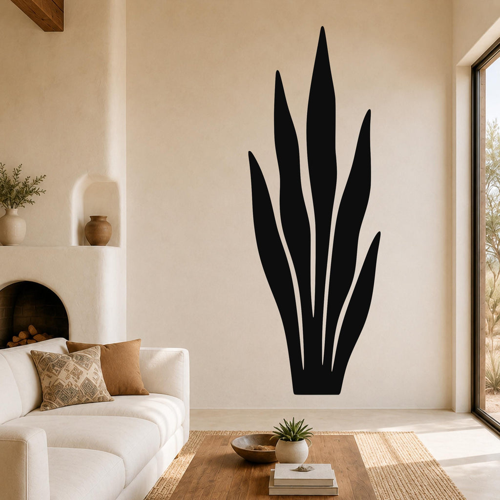 Black metal snake plant wall art with leaf cutouts, mounted on a living room wall above a sofa.