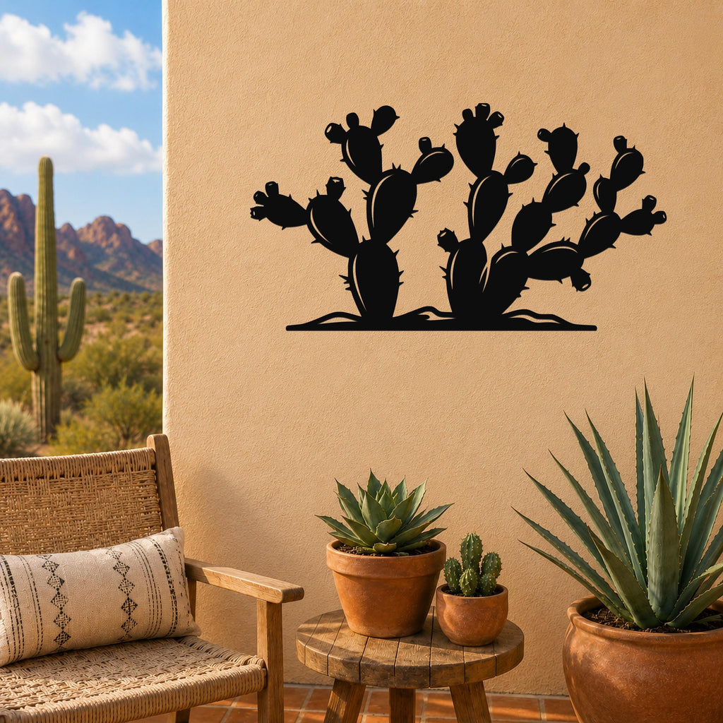 Black metal wall art in a prickly pear cactus silhouette, mounted on a tan outdoor wall above a small wooden table with potted succulents.