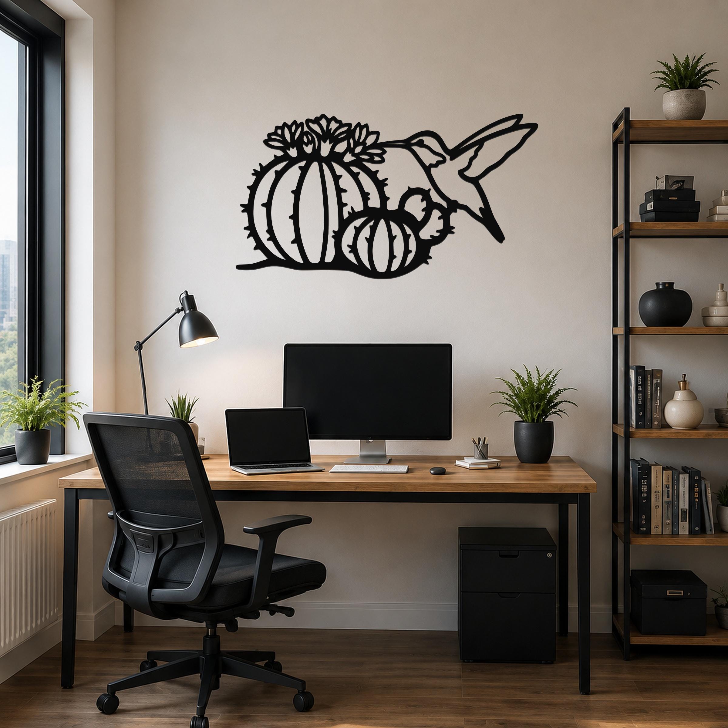 Black metal wall art featuring a hummingbird and barrel cactus with flower cutouts, mounted above a wooden desk in a home office.