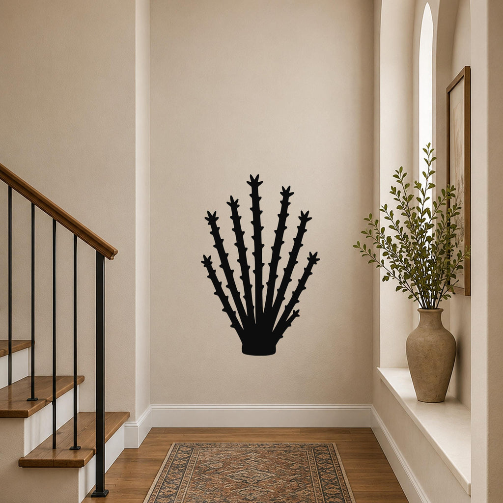 Black metal ocotillo wall art with spiky branch cutouts, mounted on a hallway wall above a patterned rug near a staircase.