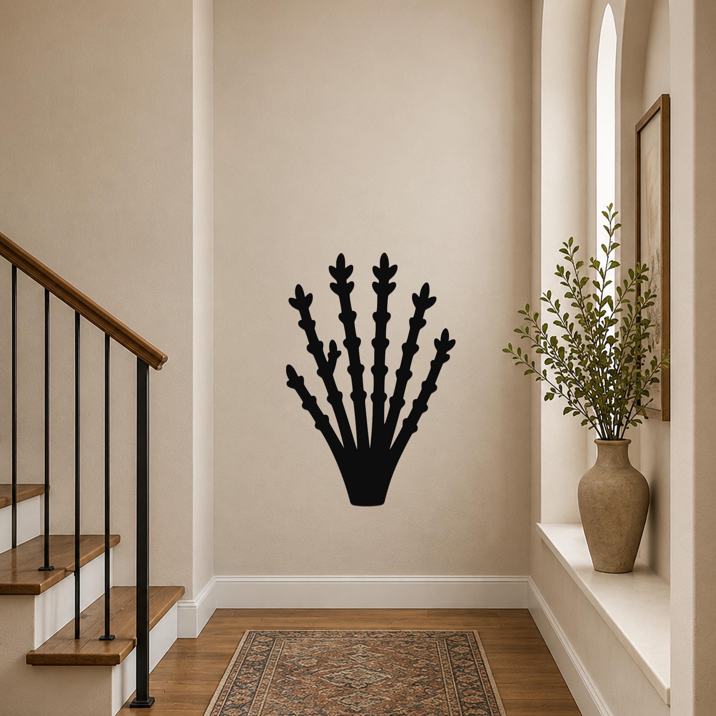 Black metal ocotillo wall art with branching cutouts, mounted on a hallway wall above a patterned rug near a staircase.