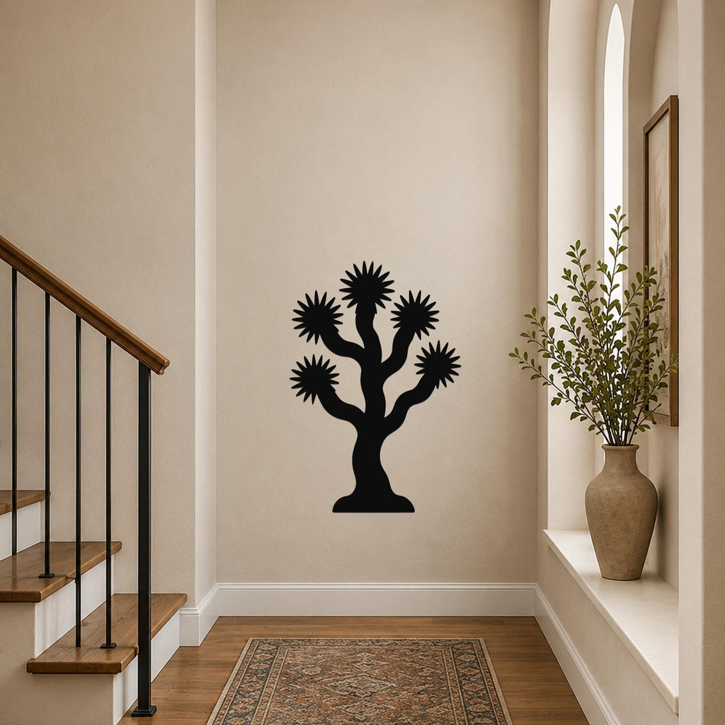 Black metal Joshua tree wall art with starburst-shaped branches, mounted on a hallway wall above a patterned rug near a staircase.